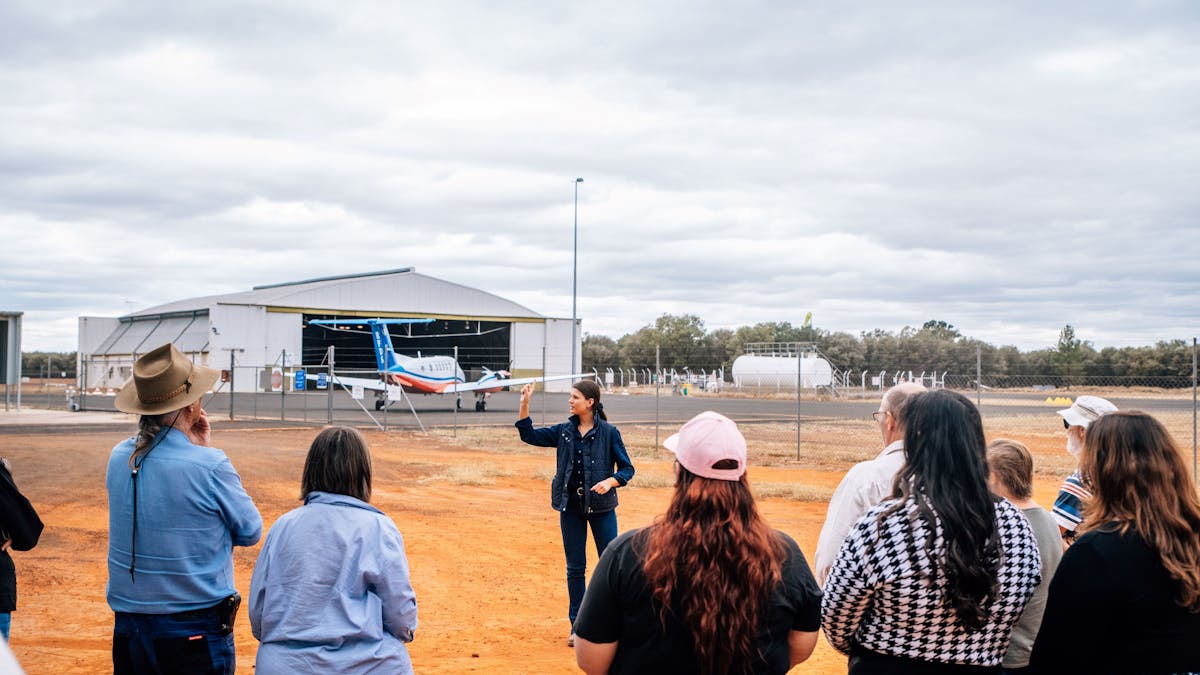 tour guide speaking to guests outside on the tour with the RFDS plane at the WWII hangar