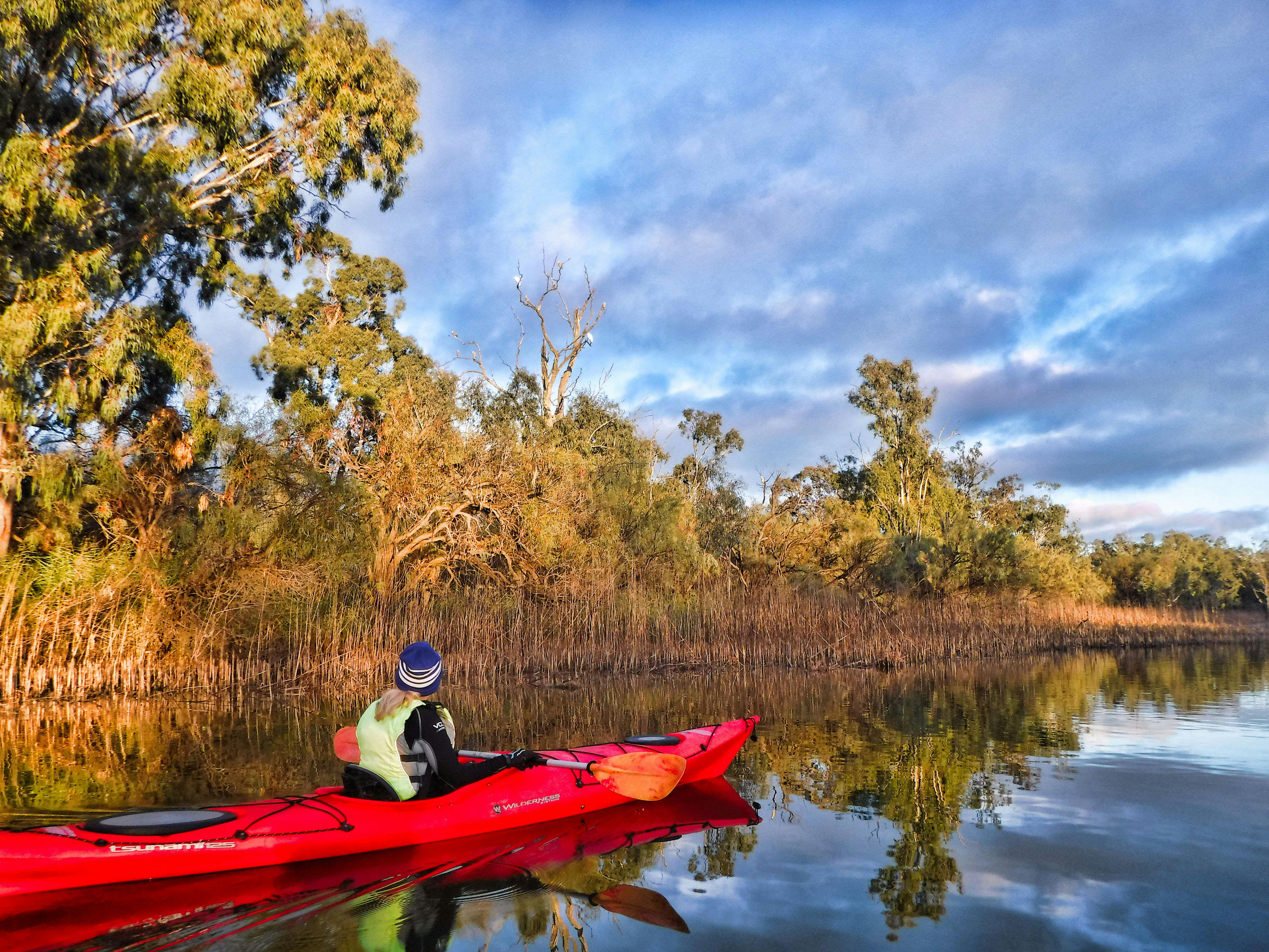 Kayaker in middle distance on creek, with lovely reflections.