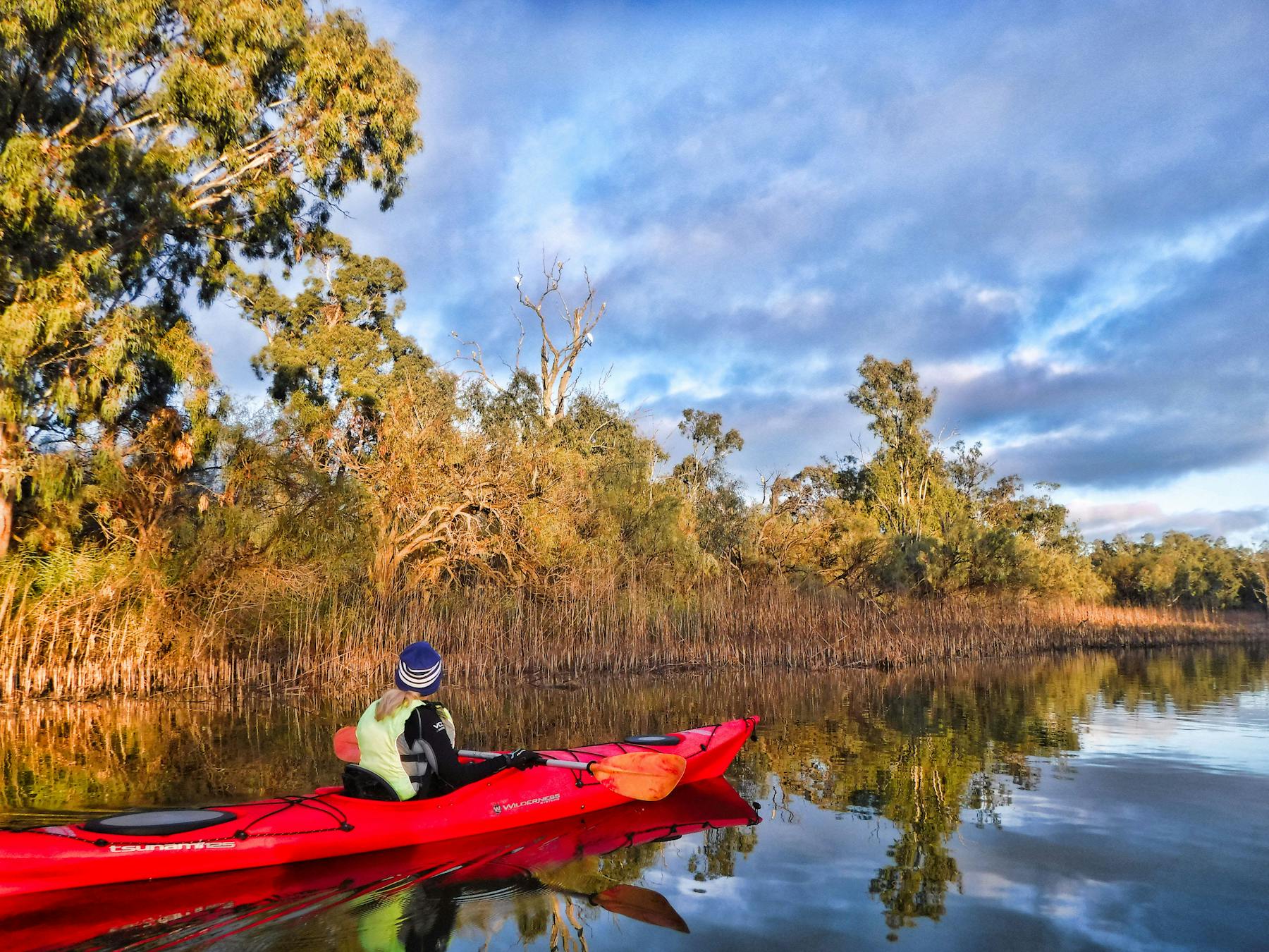 Kayaker in middle distance on creek, with lovely reflections.