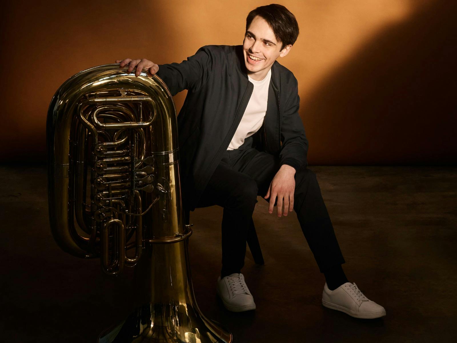A photo of ASO Principal Tuba with his instrument in a studio setting.