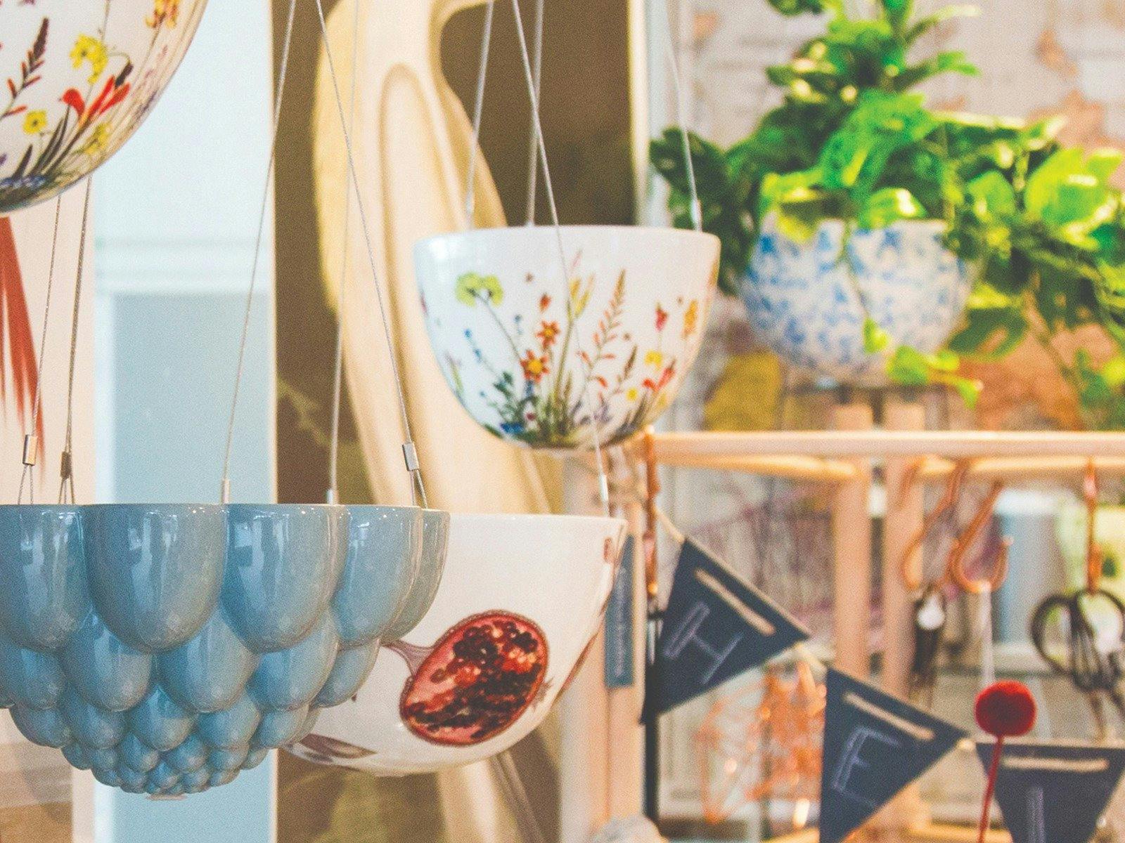 Grey ceramic jelly mould hanging planter in the foreground with botanical print ceramic hanging ...