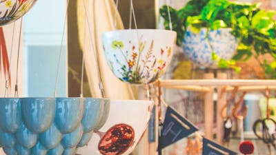 Grey ceramic jelly mould hanging planter in the foreground with botanical print ceramic hanging ...