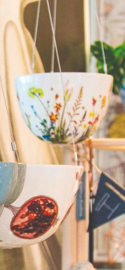 Grey ceramic jelly mould hanging planter in the foreground with botanical print ceramic hanging ...