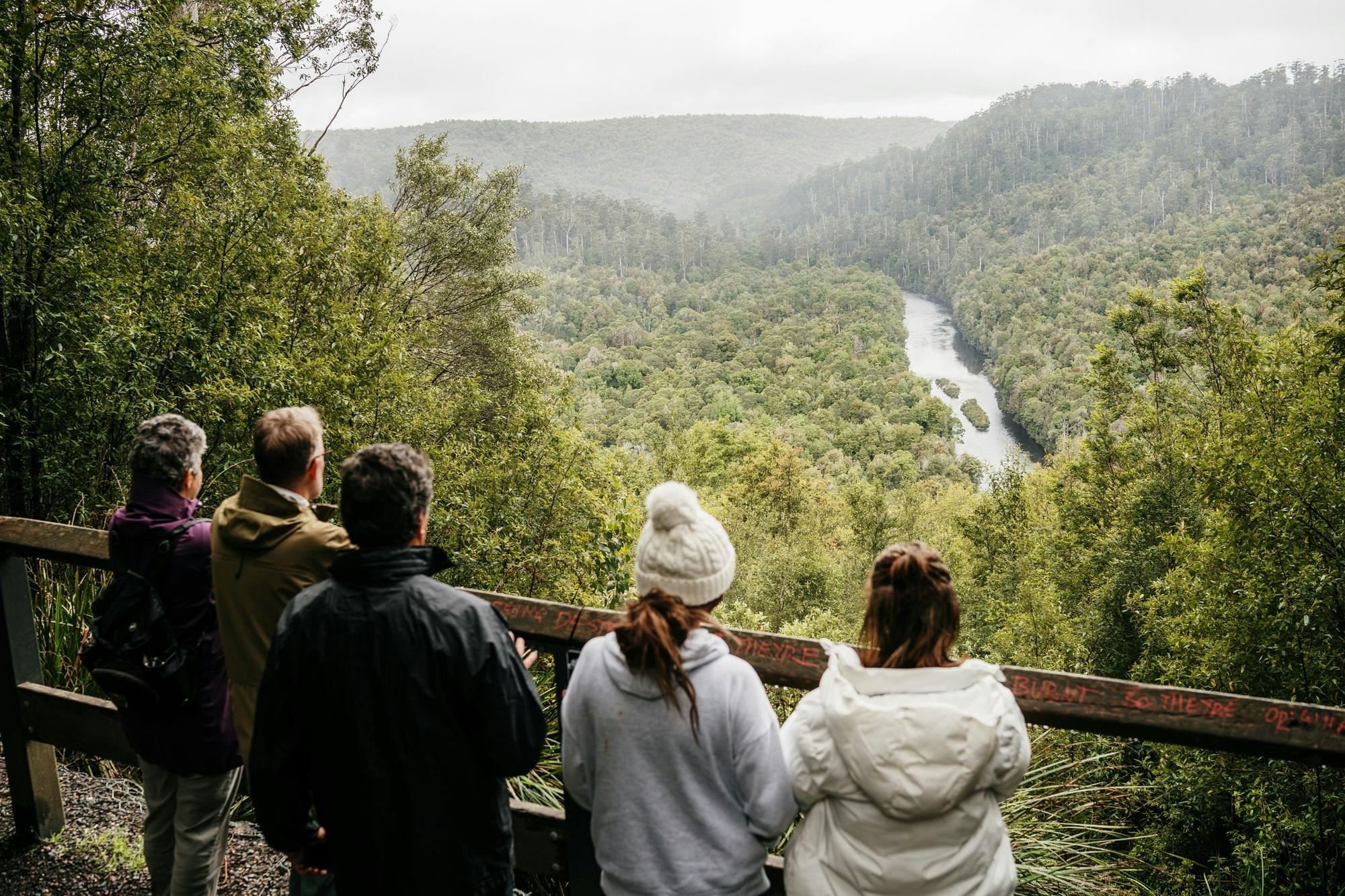 Rob and 4 tour guests looking out at the Arthur River and vast landscape of trees at Sumac Lookout