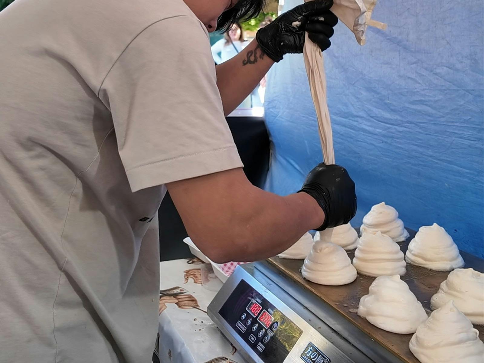 Vendor piping soufflé pancake batter mounds onto a griddle