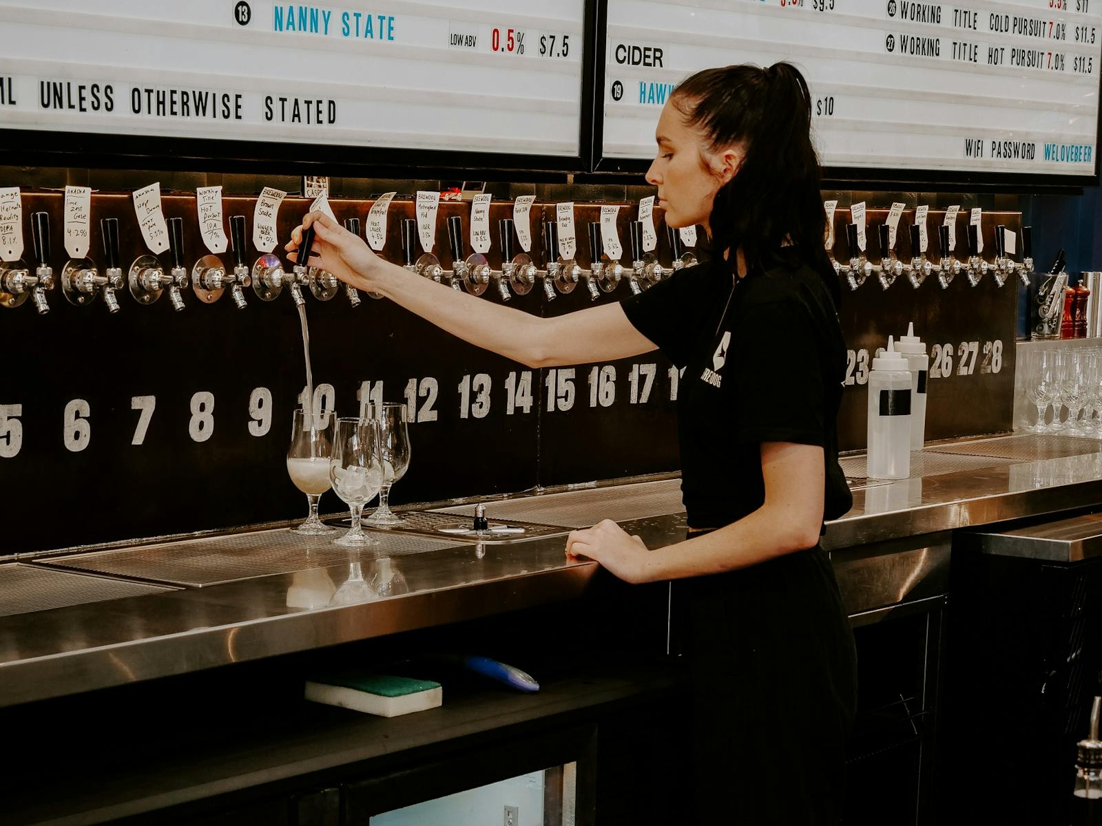 woman pouring beer from kegged tap woman pouring beer from kegged tap