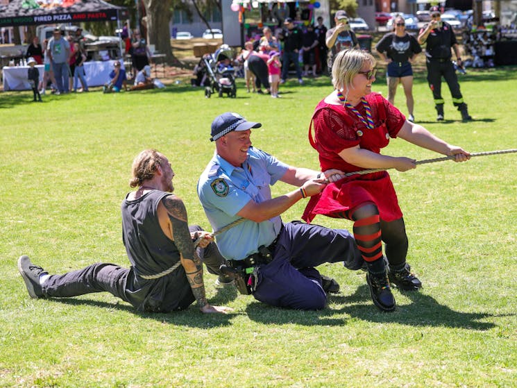 The image shows three people doing tug of war, with the crowd watching on.
