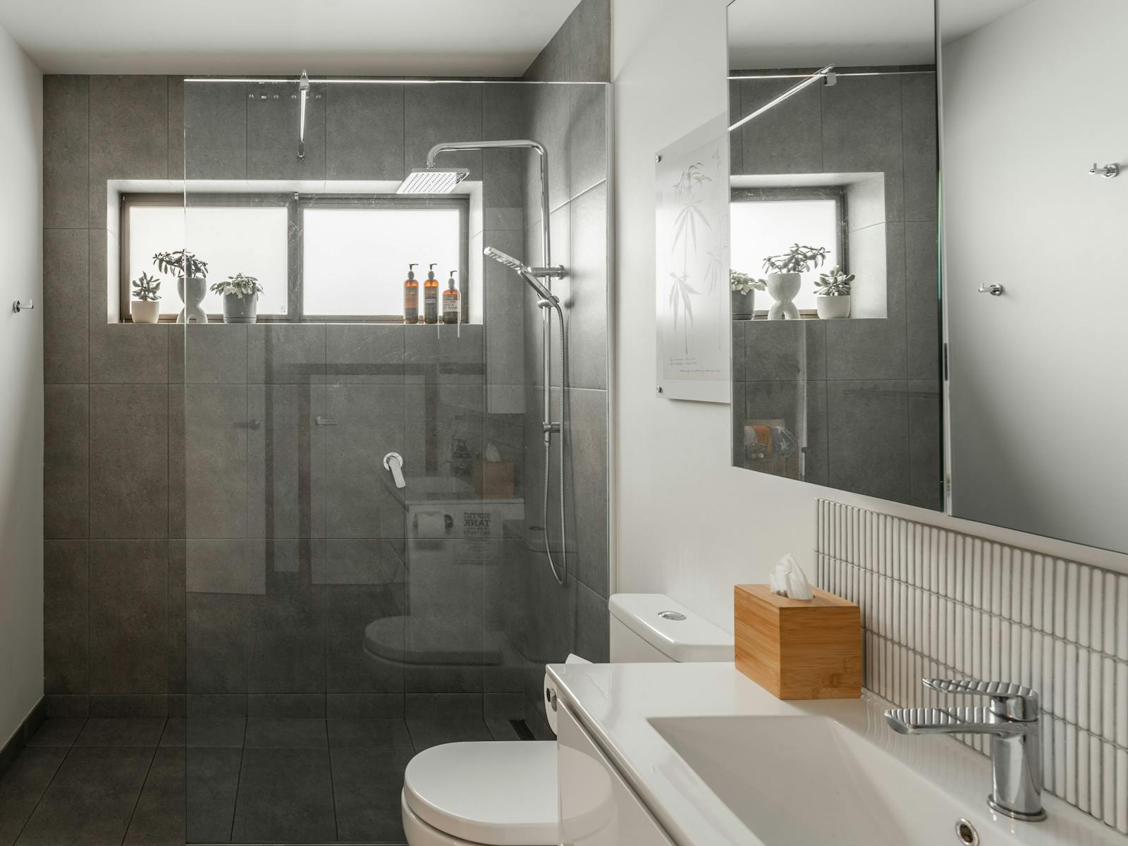 A modern bathroom with large walk-in shower, toilet and vanity unit.