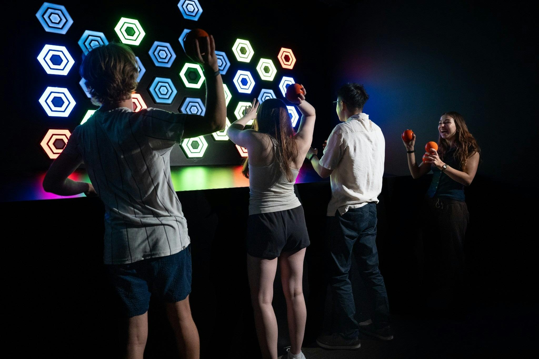 Friends enjoying an exciting interactive ball-throwing challenge at Power Play Sydney.