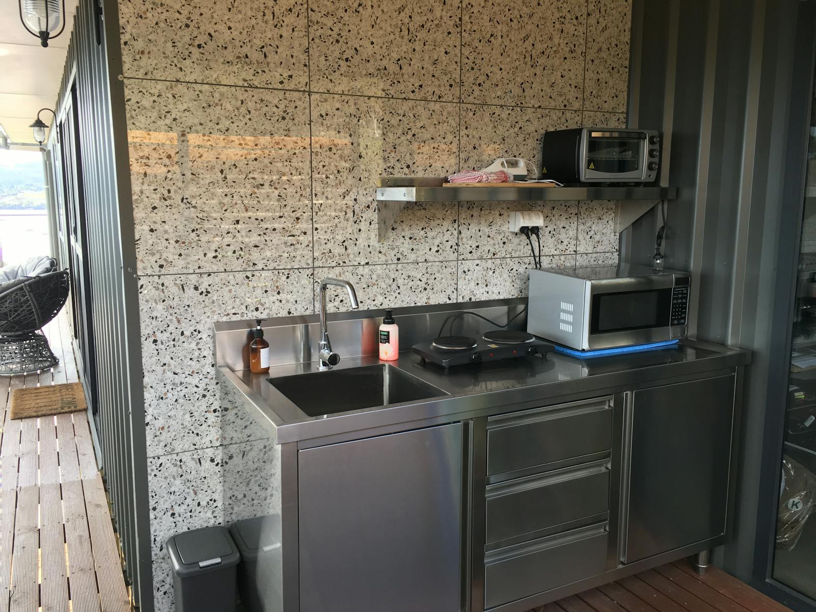 Stainless steel outdoor kitchen with cooking facilities and utensils, crockery and cutlery to cook.