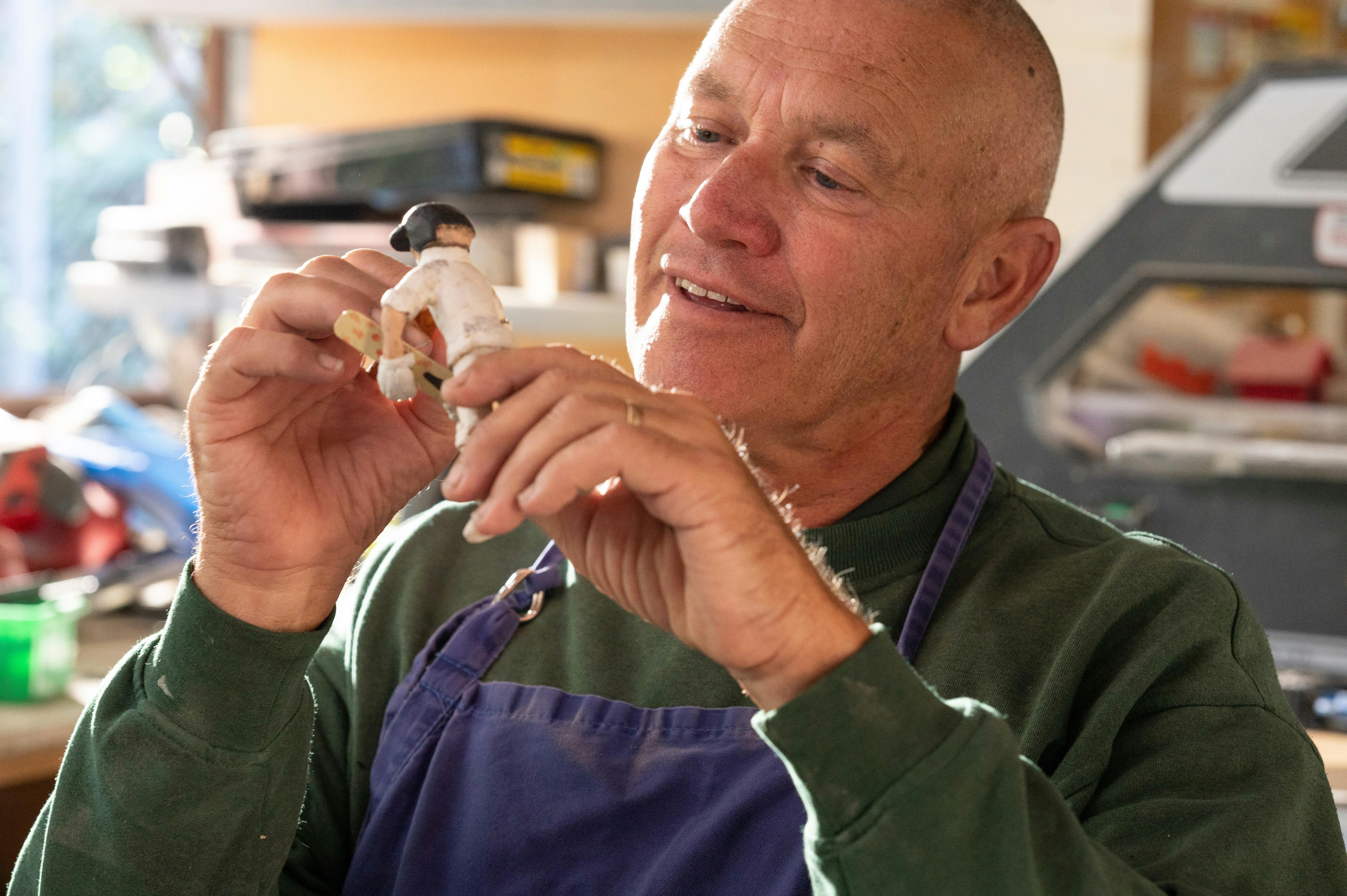 A man creates a small figurine by hand