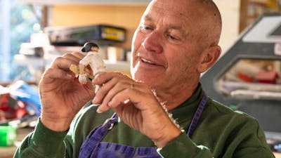 A man creates a small figurine by hand