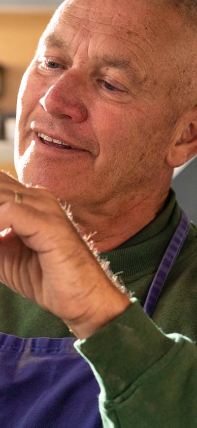 A man creates a small figurine by hand