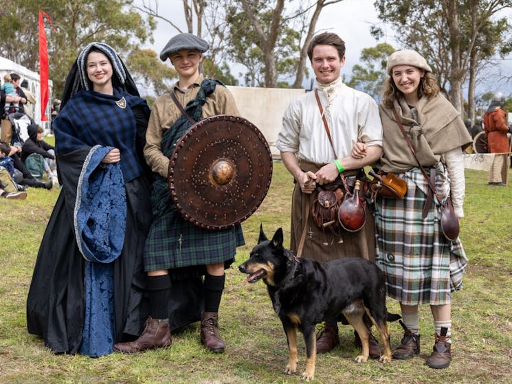 Four festival attendees dressed in traditional clothing with their dog at the festival