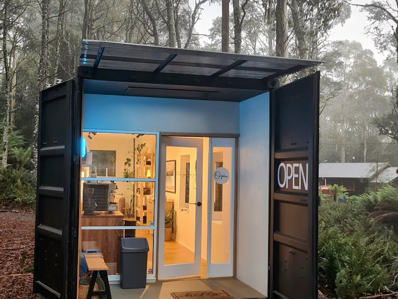 A renovated shipping container being used as an art gallery in a wilderness scene on a foggy day