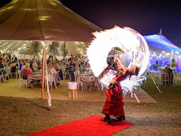 Fire twirler at ball event under Sperry tent
