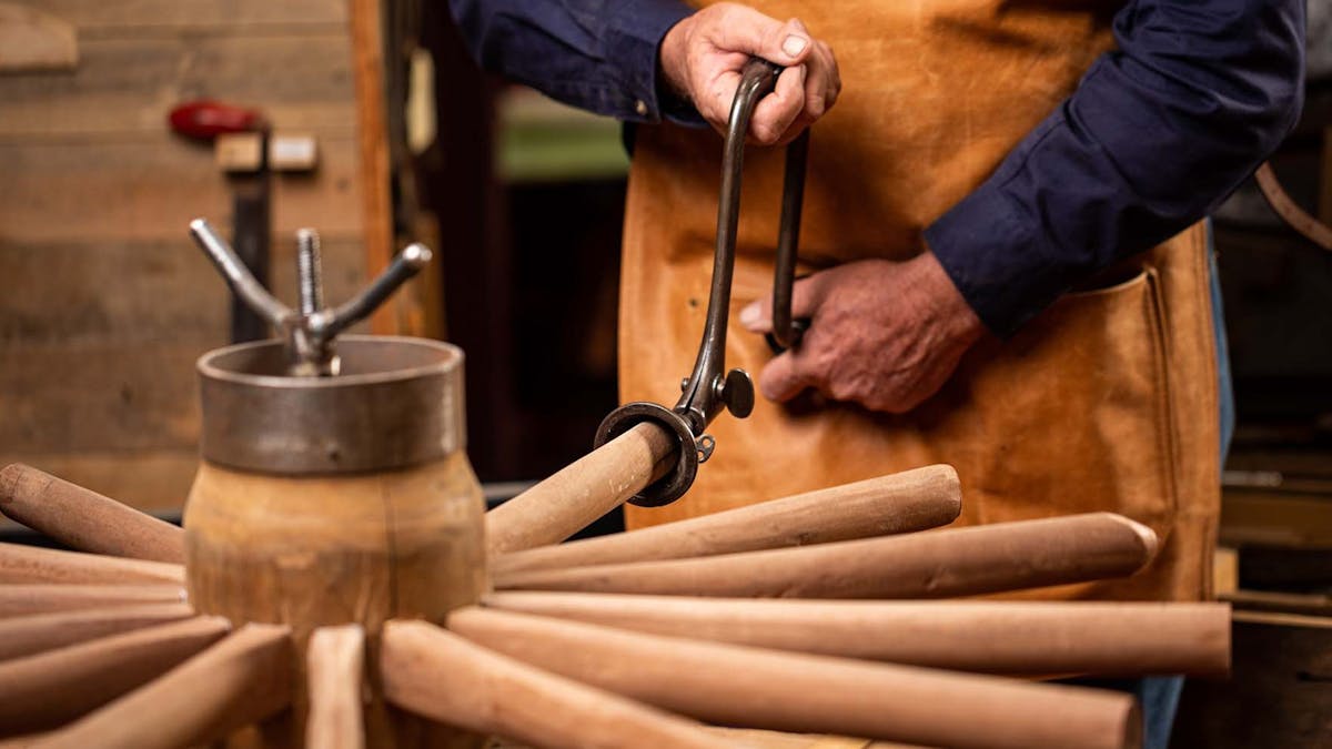 Artisan wheelwright working on a wheel in the museum factory