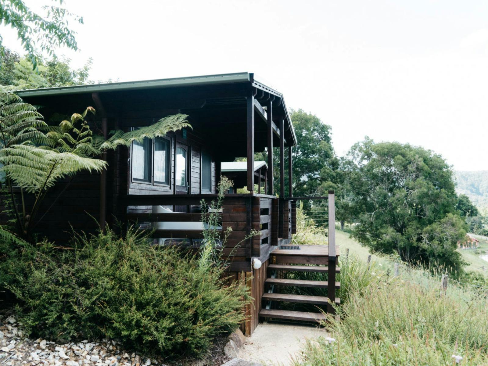 A pine cabin with wooden steps leading up to it, overlooking nature