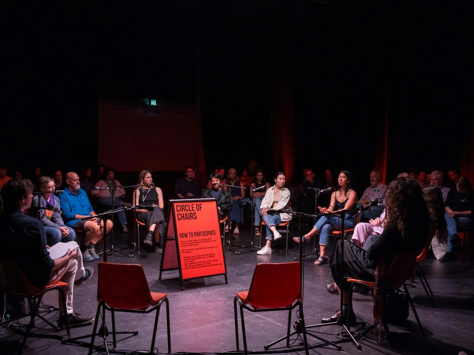people sitting in charis in a circle with microphones in front of them.