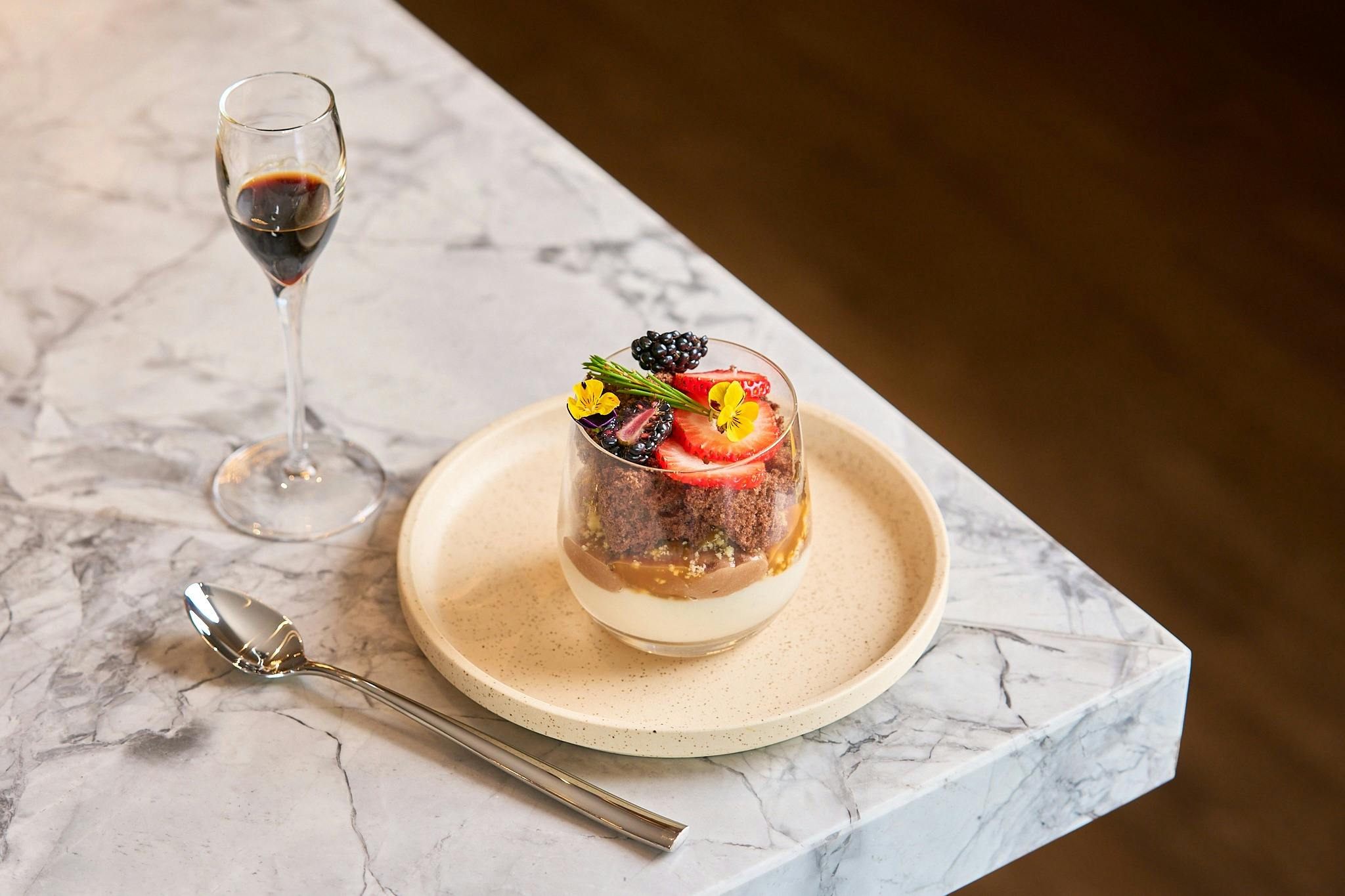 Small sized dessert served in a glass with spoon on marble bench in the Gateway bar