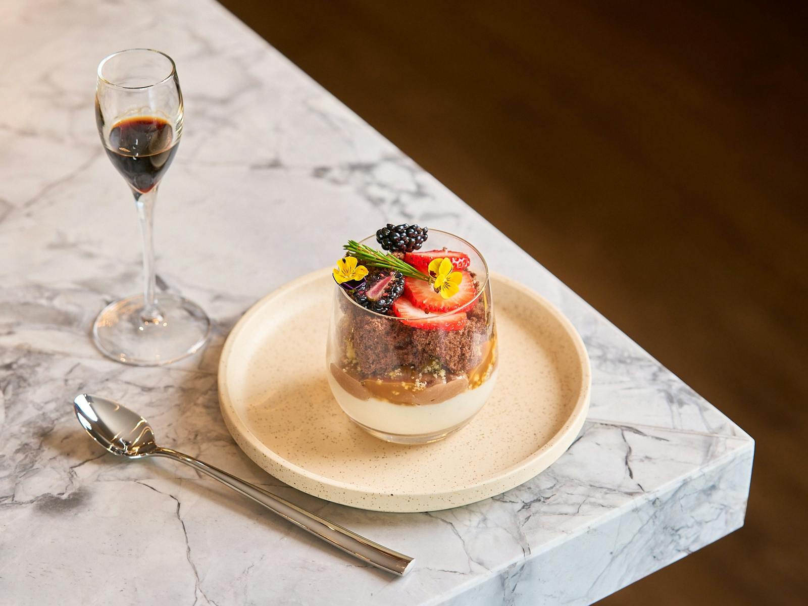 Small sized dessert served in a glass with spoon on marble bench in the Gateway bar