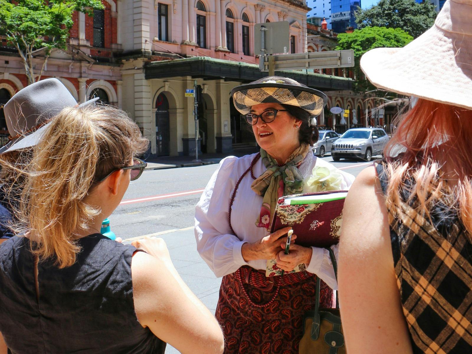A woman dressed in old timey clothing leads a group through the city