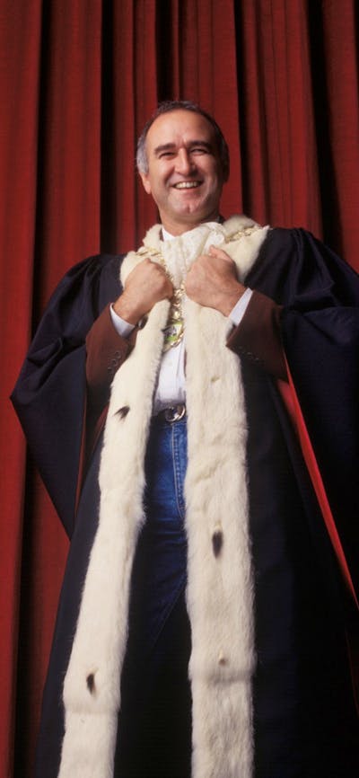 Man stands wearing a royal cape smiling at camera
