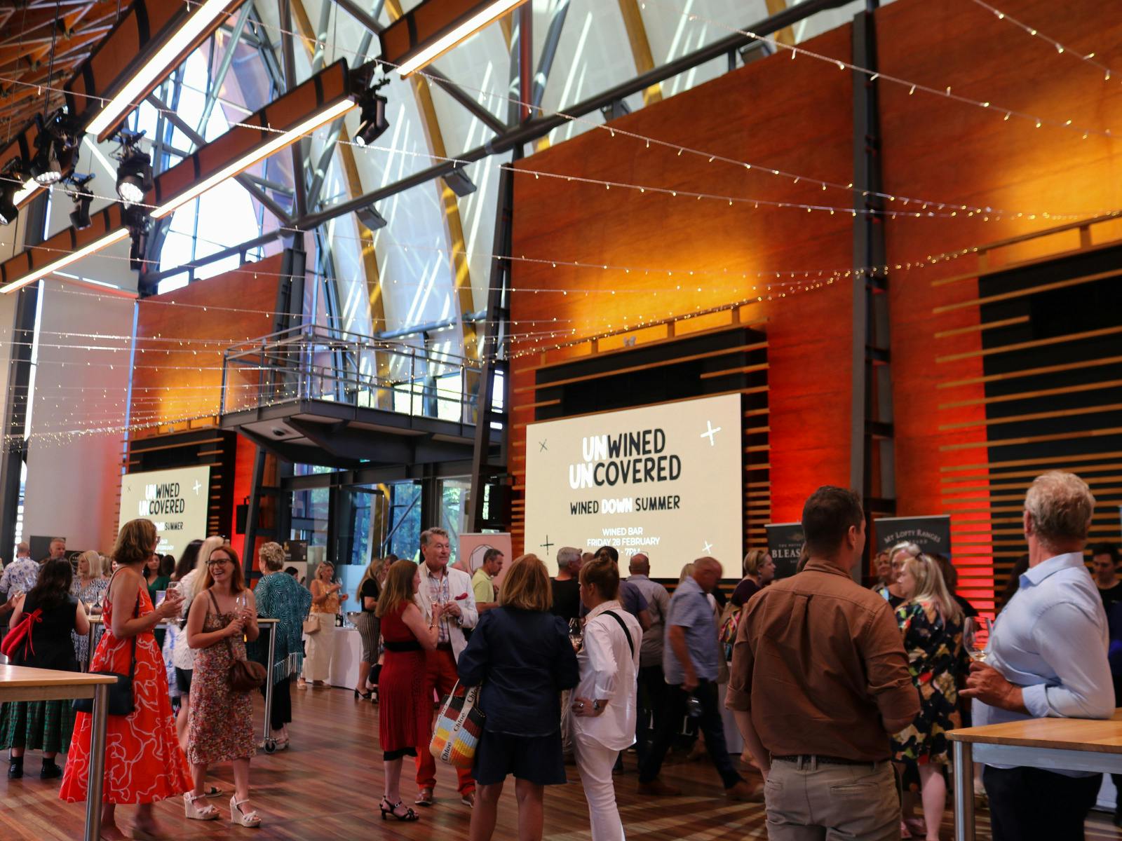 Guests mingle at a lively wine event in a soaring modern hall