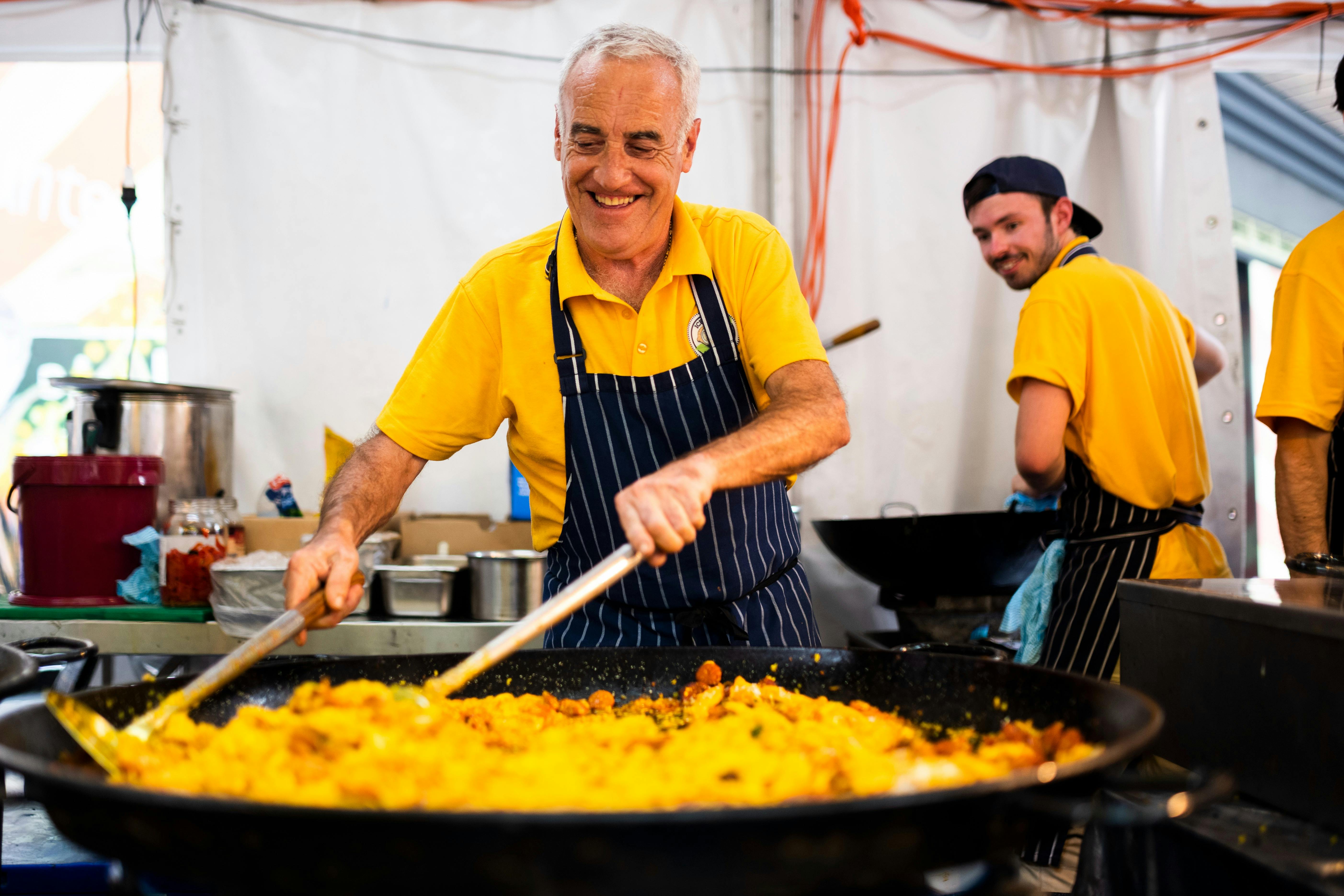 A man cooking paella in a large frying pan