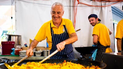 A man cooking paella in a large frying pan