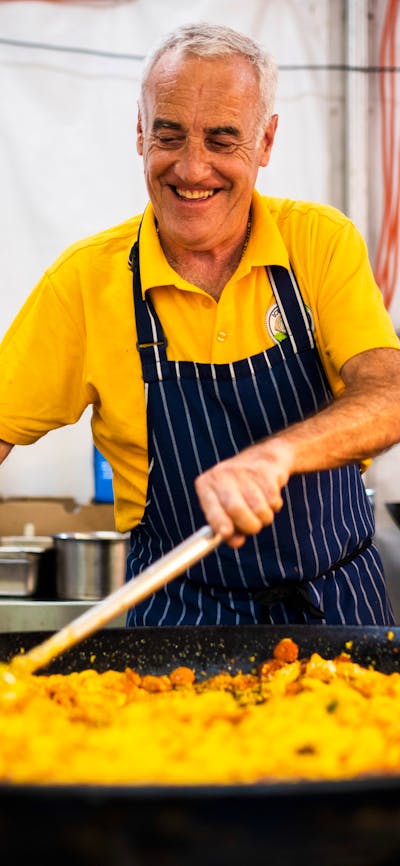 A man cooking paella in a large frying pan