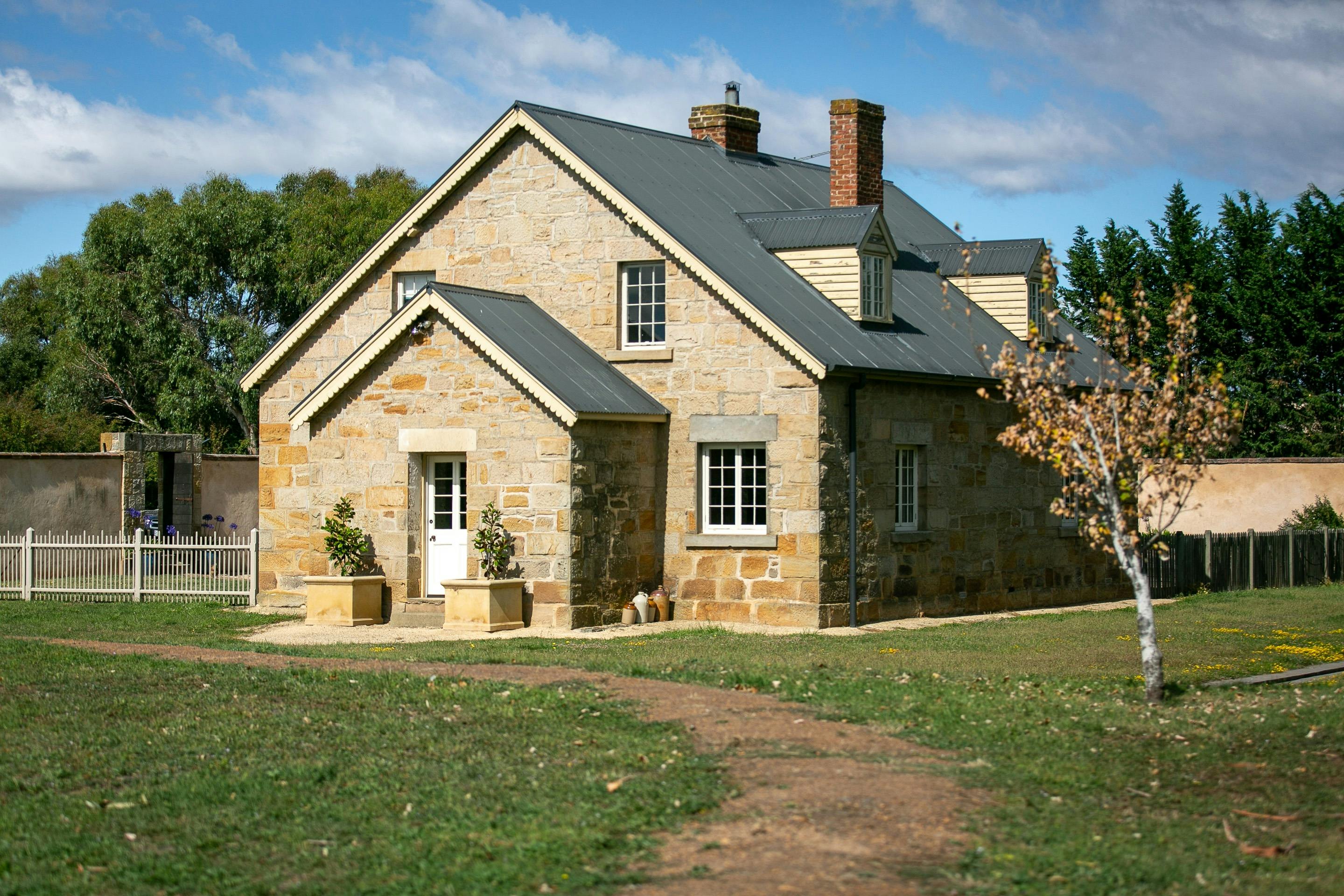 Historic sandstone two storey dwelling with solar lights and large planters marking the entrancce.