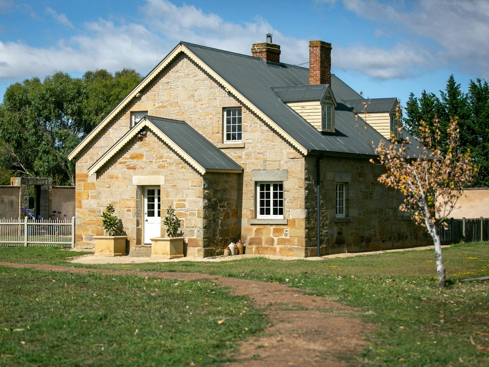 Historic sandstone two storey dwelling with solar lights and large planters marking the entrancce.