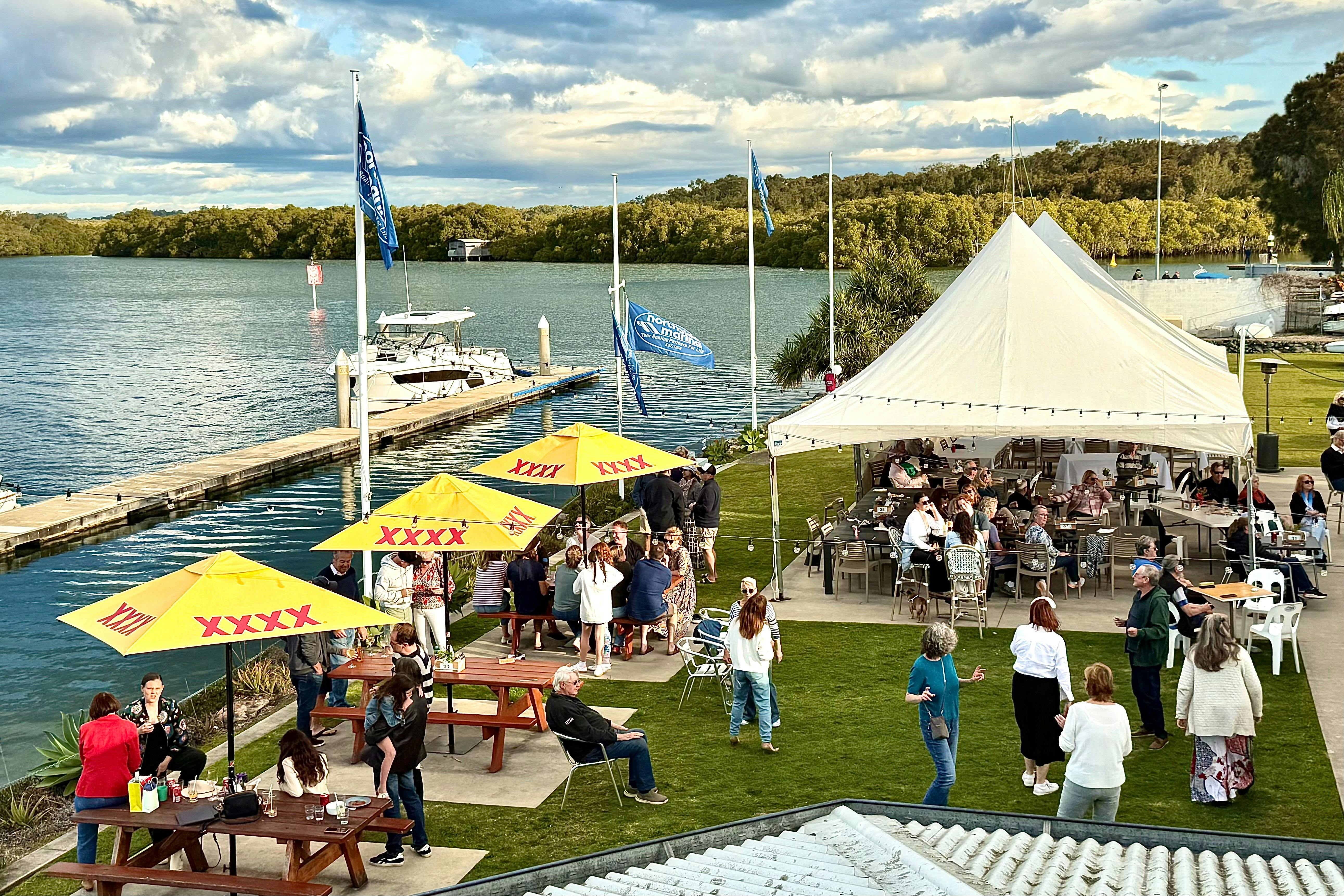 Diners sitting underneath umbrellas and Marquee enjoying water views over the Marina.