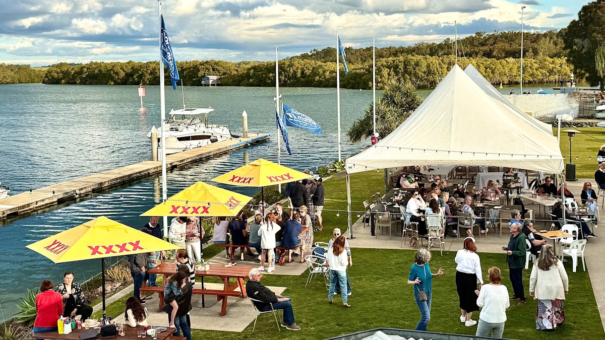 Diners sitting underneath umbrellas and Marquee enjoying water views over the Marina.