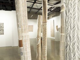 Detail image of larrakitj and bark paintings install at praxis ART SPACE,  in Adelaide SA
