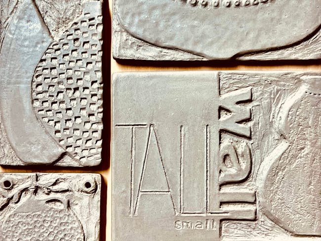 A photograph of ceramic tiles with shapes and textures carved into them