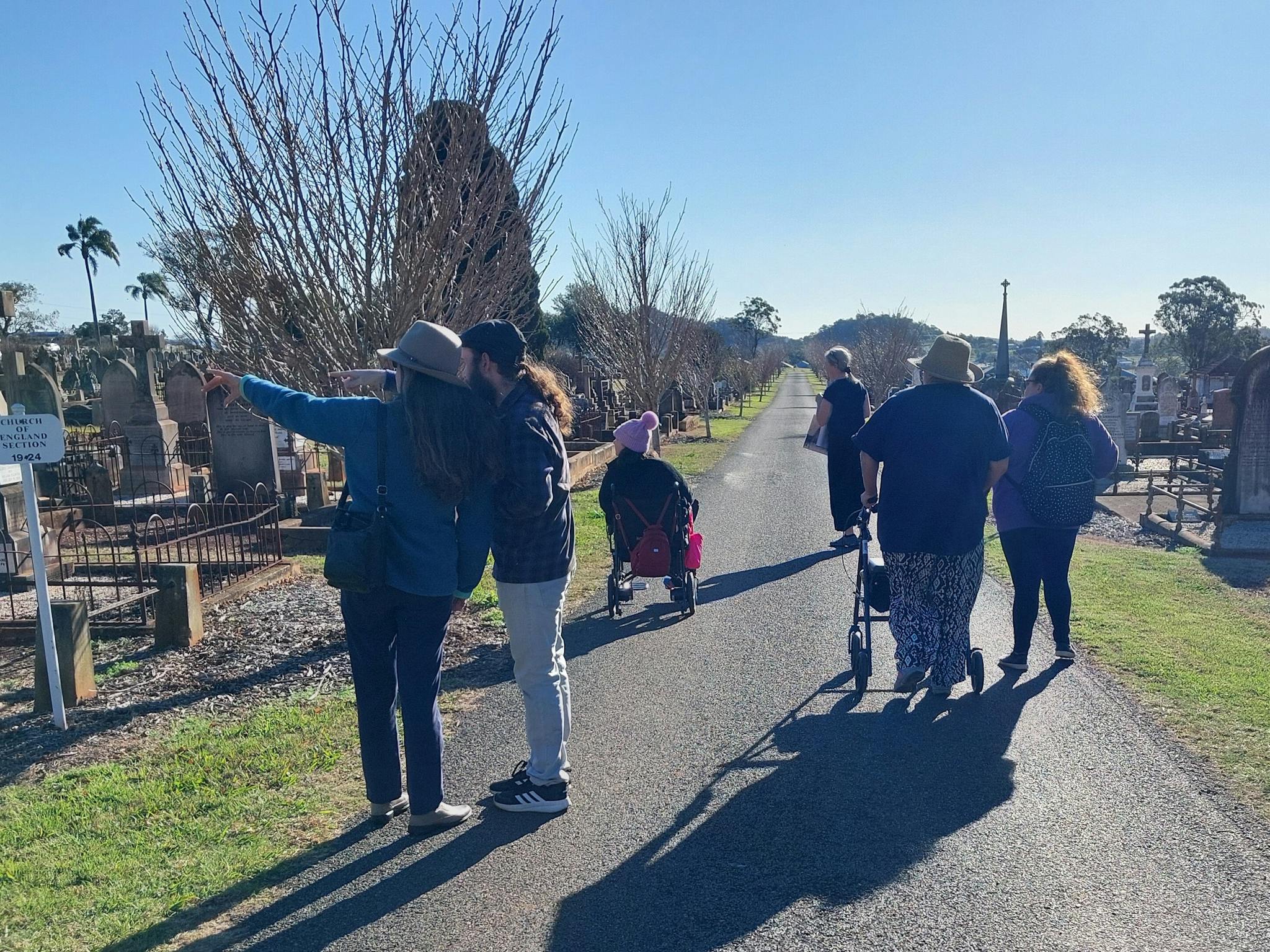 A group of people, some in wheelchairs, with wheelie walkers, travelling down a bitumen avenue A group of people, some in wheelchairs, with wheelie walkers, travelling down a bitumen avenue