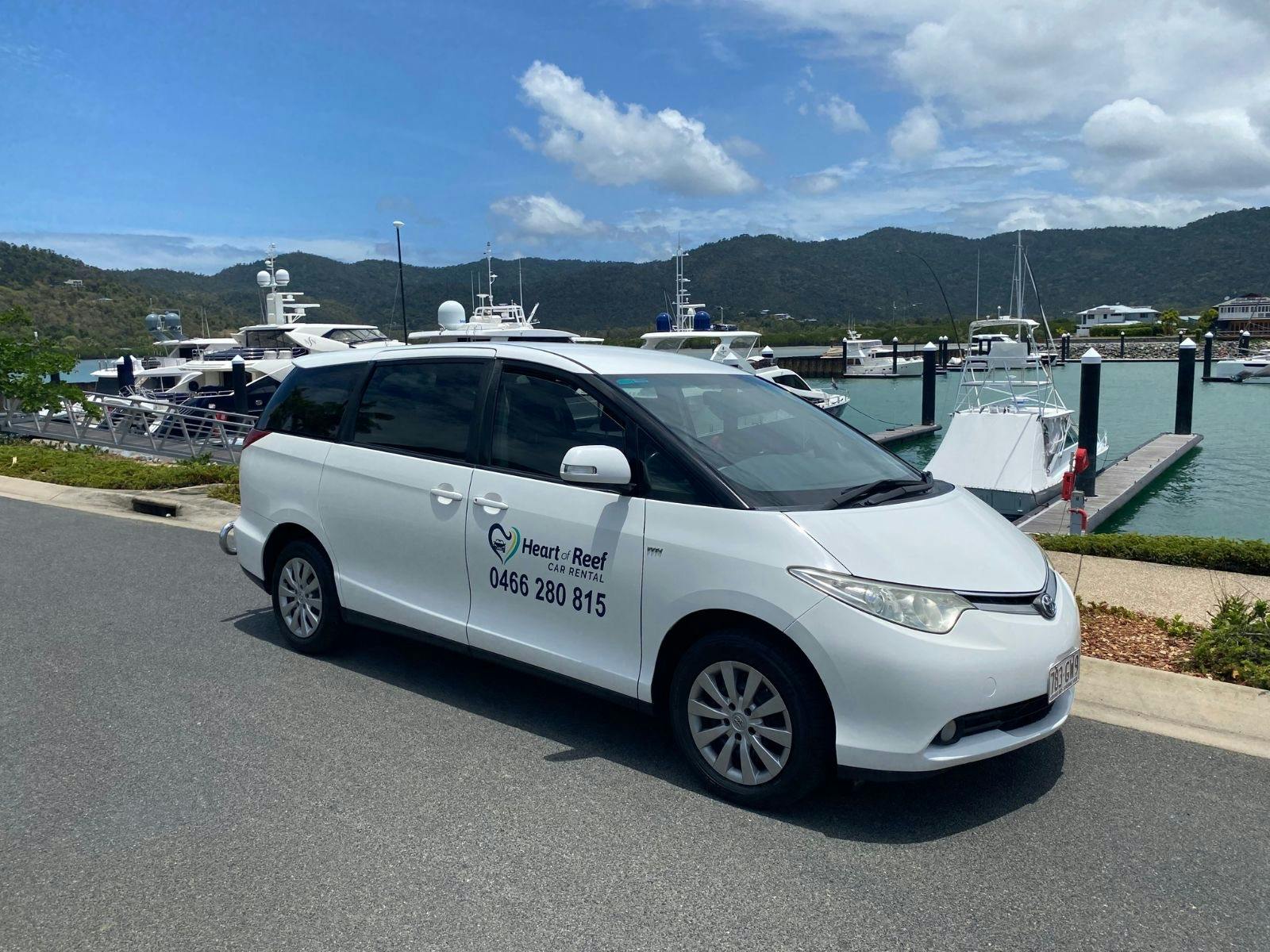 8 seater tarago car for hire with Airlie Beach marina background