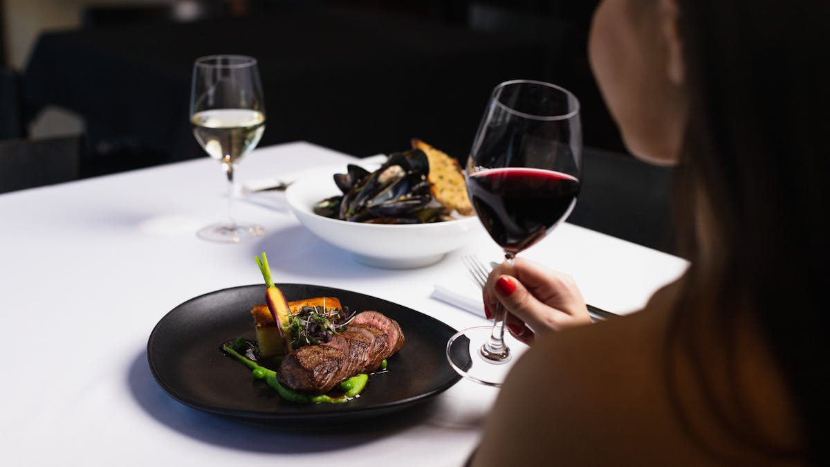 Woman enjoining a meal with wine at Lennons Restaurant & Bar - Level Two Hyatt Regency Brisbane