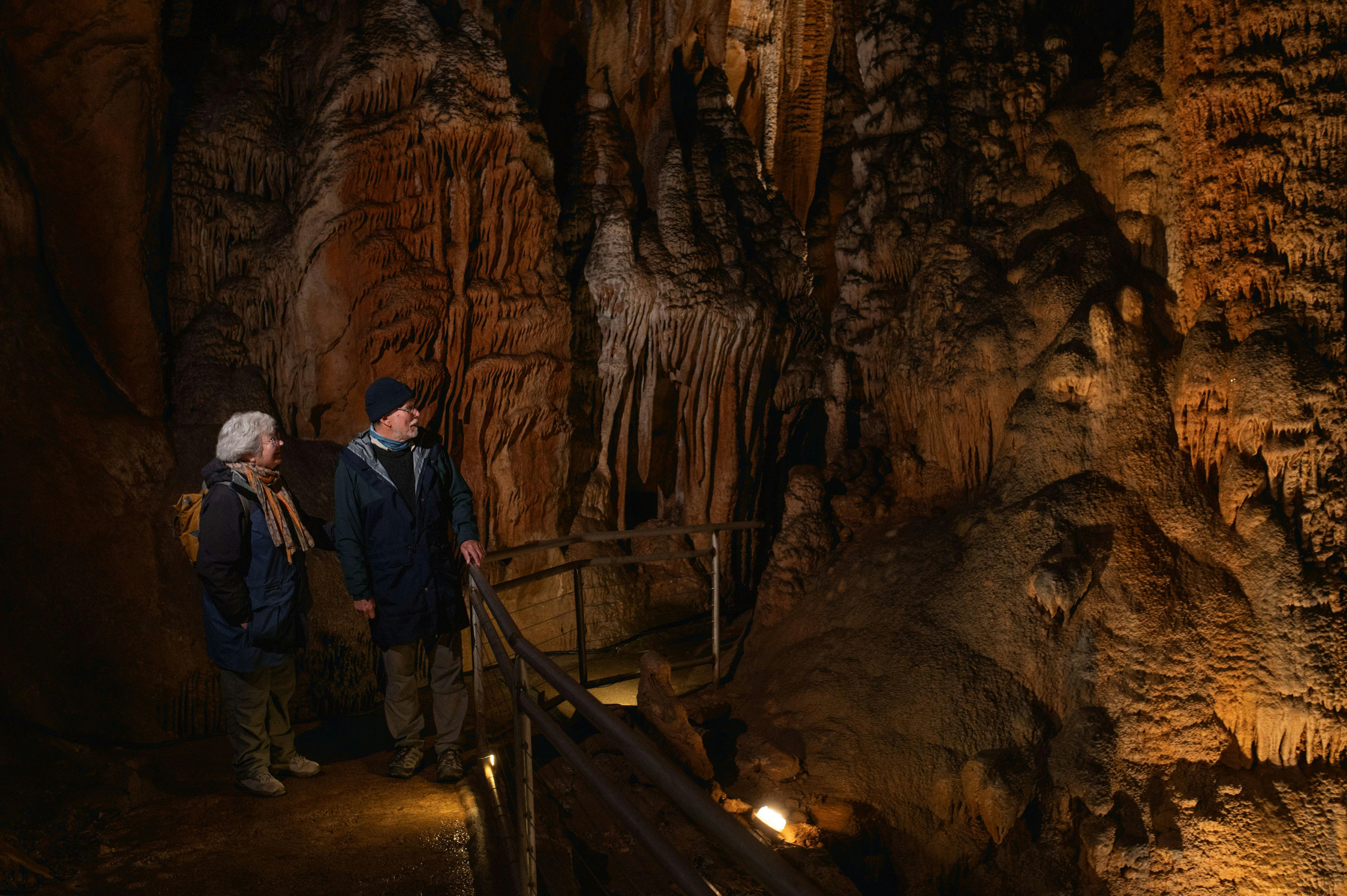 A man and a woman standing in a cavern surrounded by stalagmites and stalactites