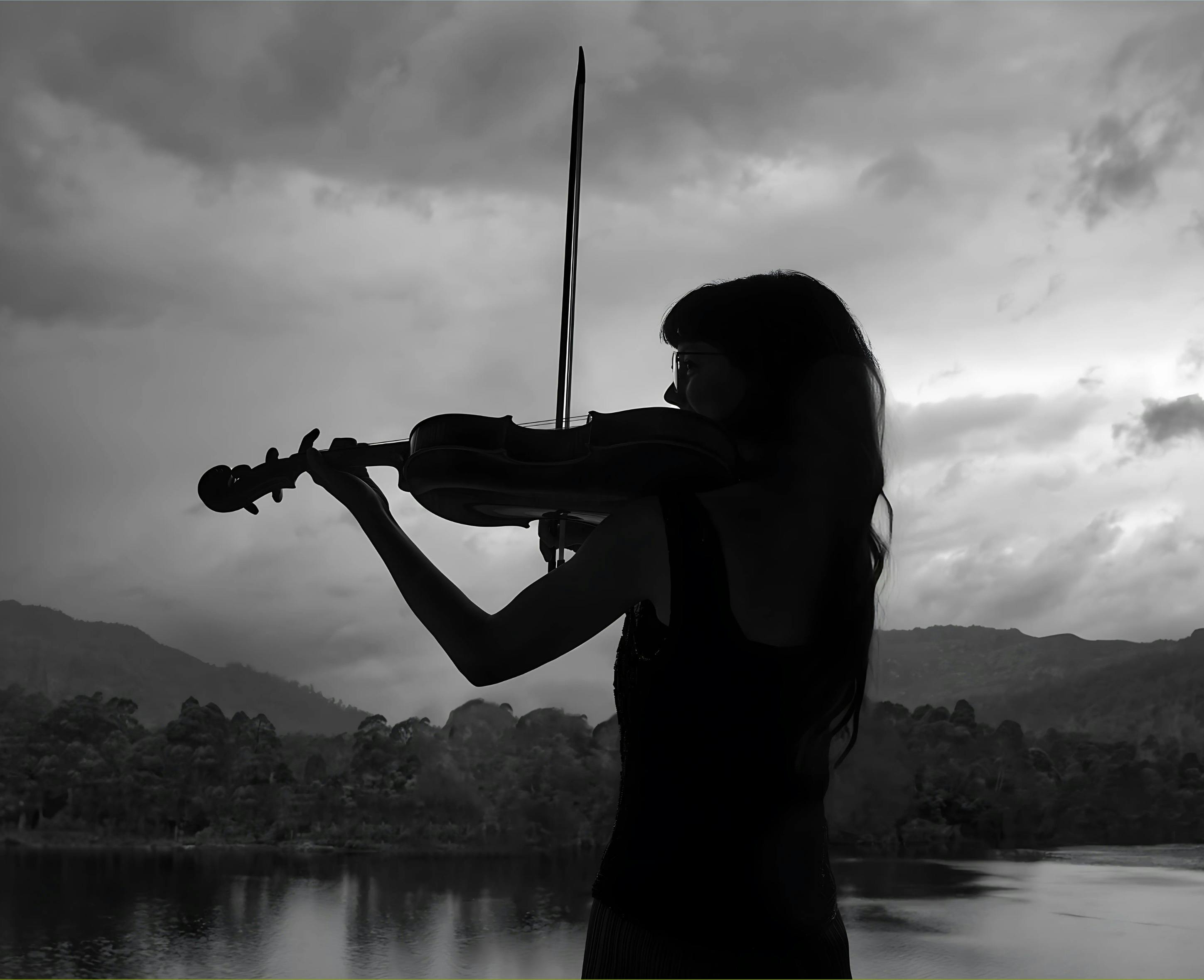 Silhouette of a woman playing violin in the Tasmanian landscape.