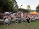 people sitting on metal benches with marquees with trees in the background