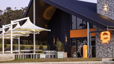 Foxdog Distillery exterior at dusk, featuring modern architecture, outdoor seating under white canop
