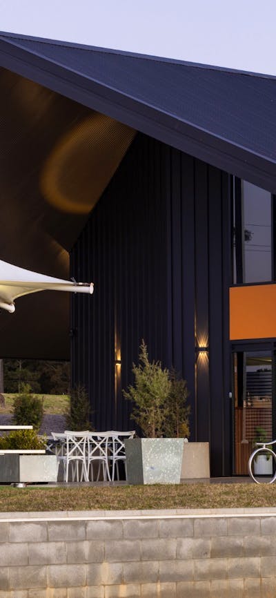 Foxdog Distillery exterior at dusk, featuring modern architecture, outdoor seating under white canop
