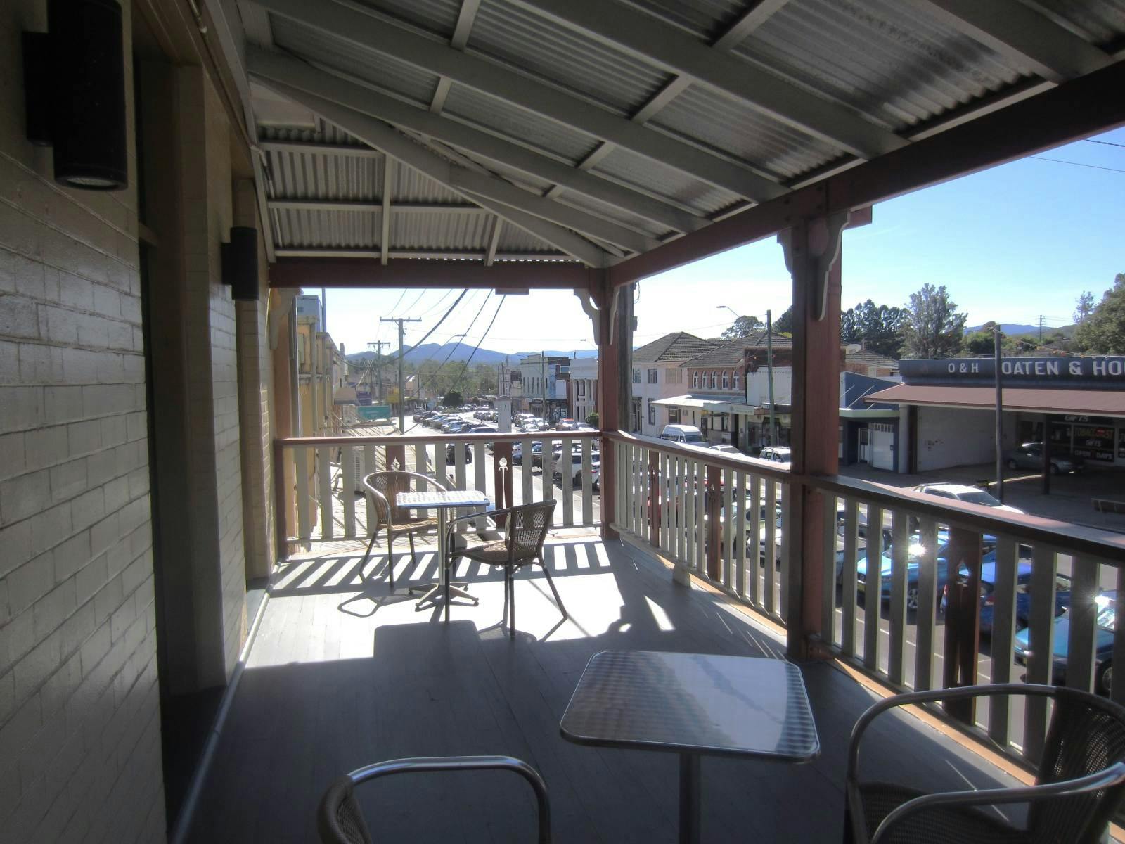 Tables and chairs on a verandah above a main street with mountains in distance