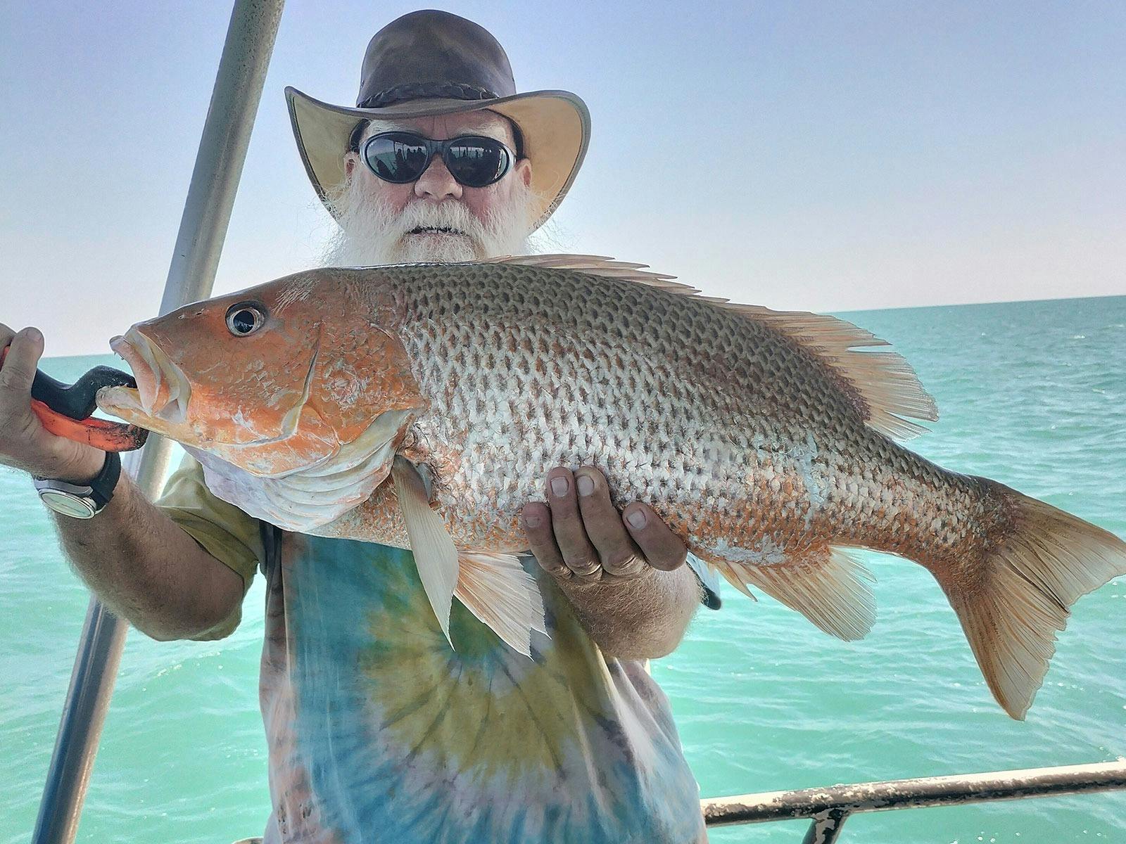 A man holding a fish on a Darwin Red Devil Charter.