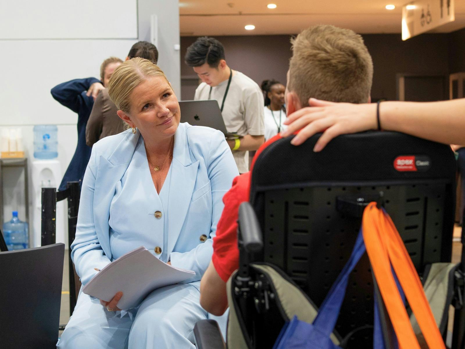 A lady in a light blue suit interviewing a young man looking for employment