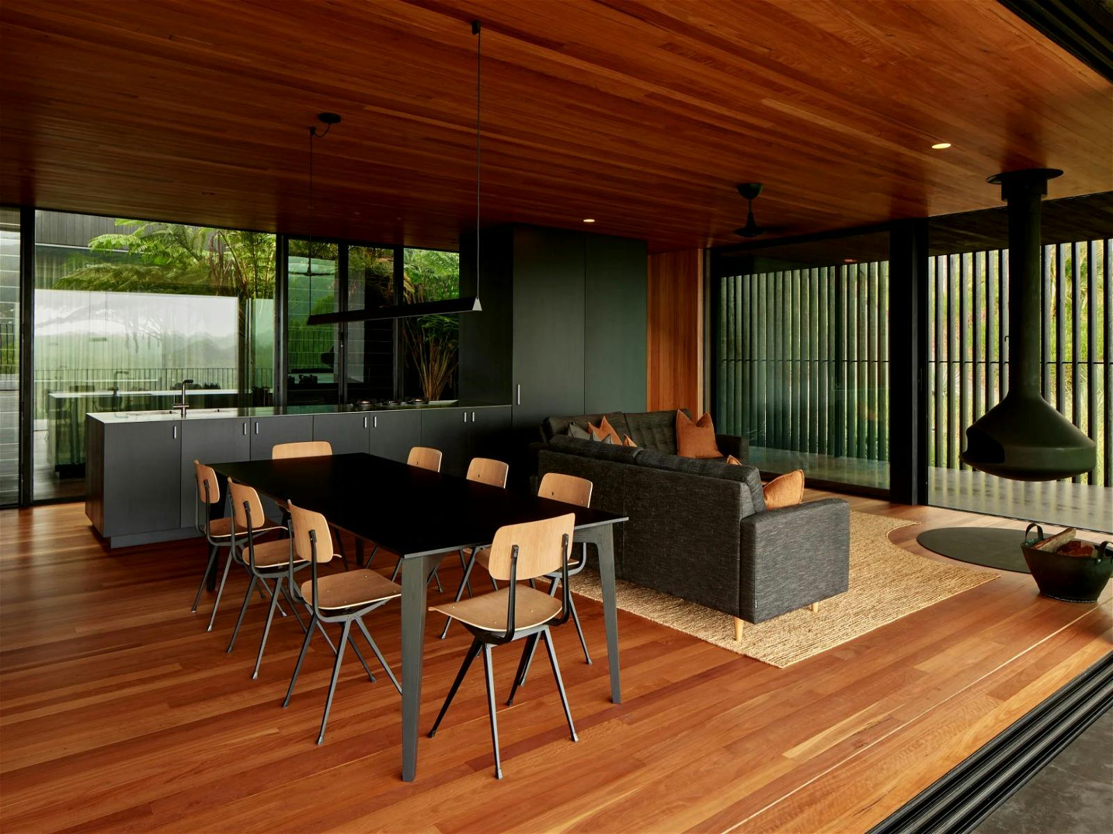 Light-filled yet chic moody interior, with large windows, open plan living, and panoramic views