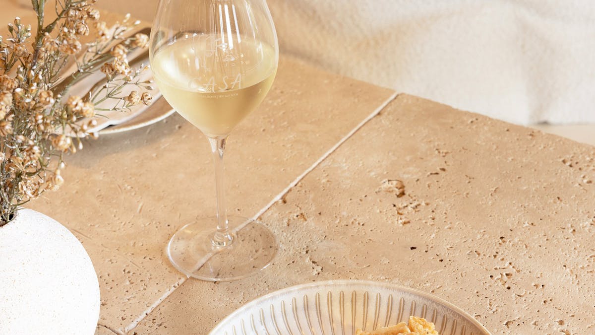 Plate of golden, crispy calamari served with lemon alongside a glass of Riesling